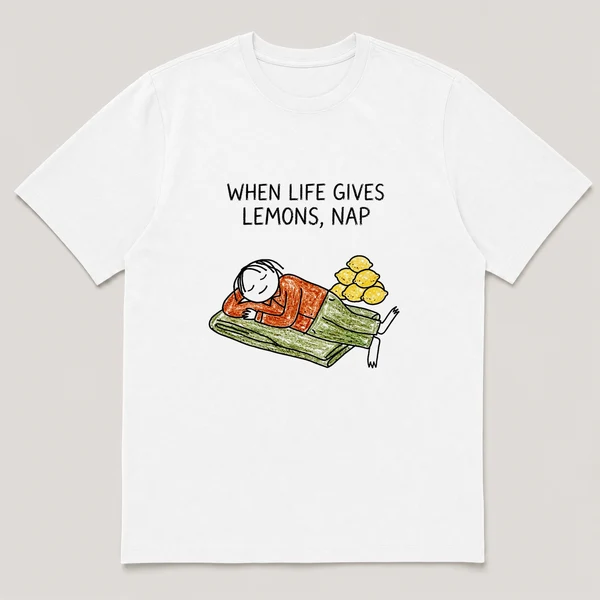 Front view of a White Tee printed with guy naps on a blanket with a pile of lemons stacked beside him and the caption WHEN LIFE GIVES LEMONS, NAP