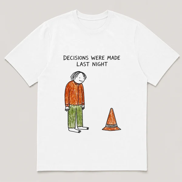 Front view of a White Tee printed with sheepish guy stares at a traffic cone sitting in the middle of his living room and the caption DECISIONS WERE MADE LAST NIGHT